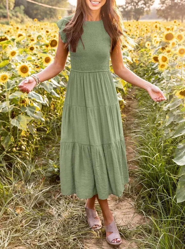 Women's sleeveless smocked midi dress with A-line skirt, airy fabric, perfect for summer occasions. Elegant and comfortable.