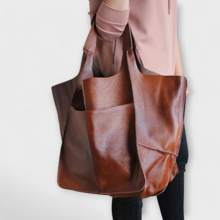 Large women's faux leather tote bag, featuring a stylish design and convenient exterior pockets.