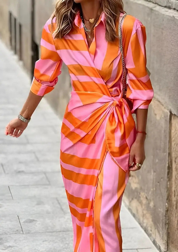 Woman confidently walking in a flowing striped wrap midi long sleeve dress, showcasing movement.